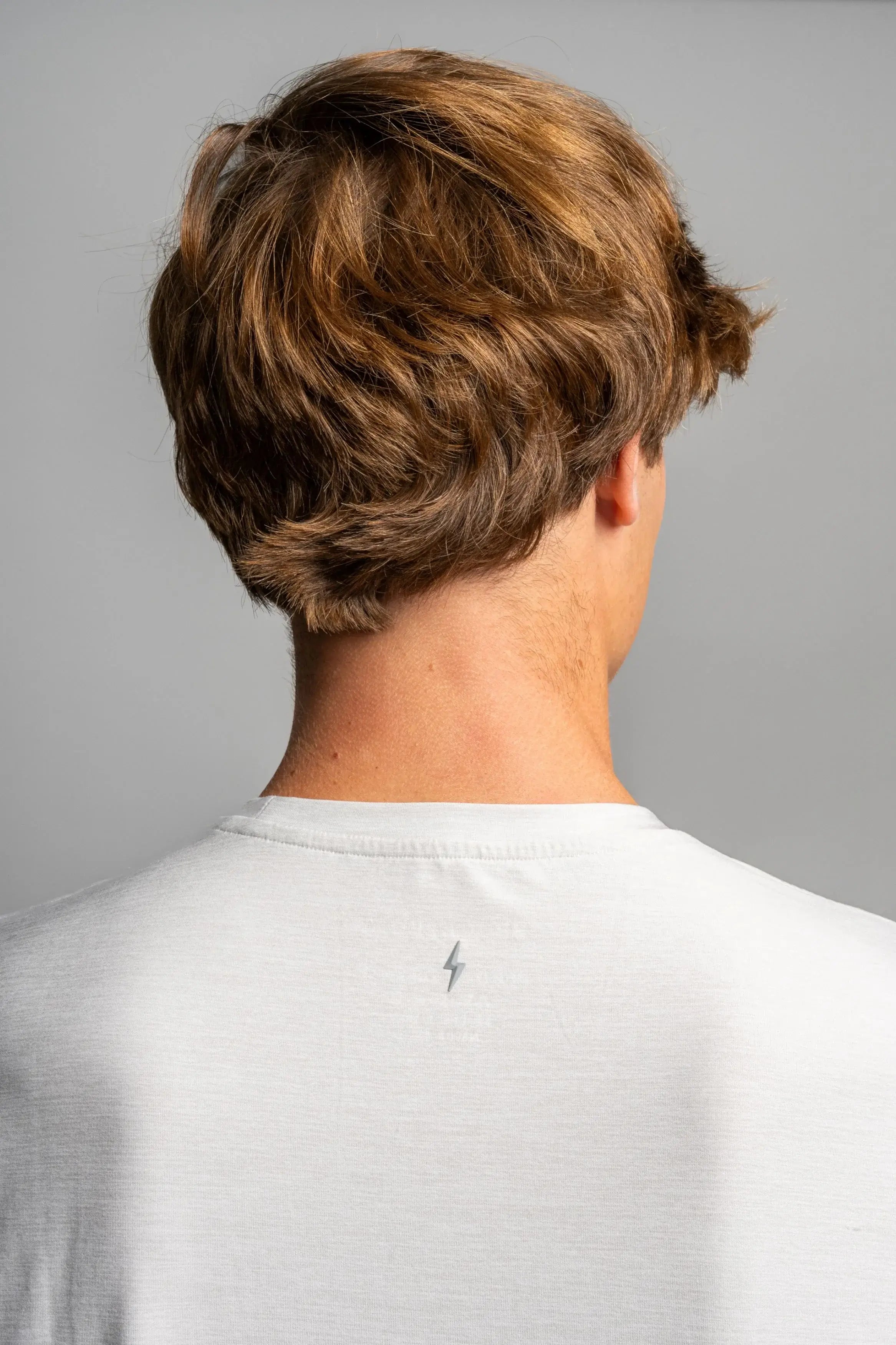 Back view of a youth wearing a grey Bruce Bolt SuperSoft T-Shirt featuring a lightning bolt design.