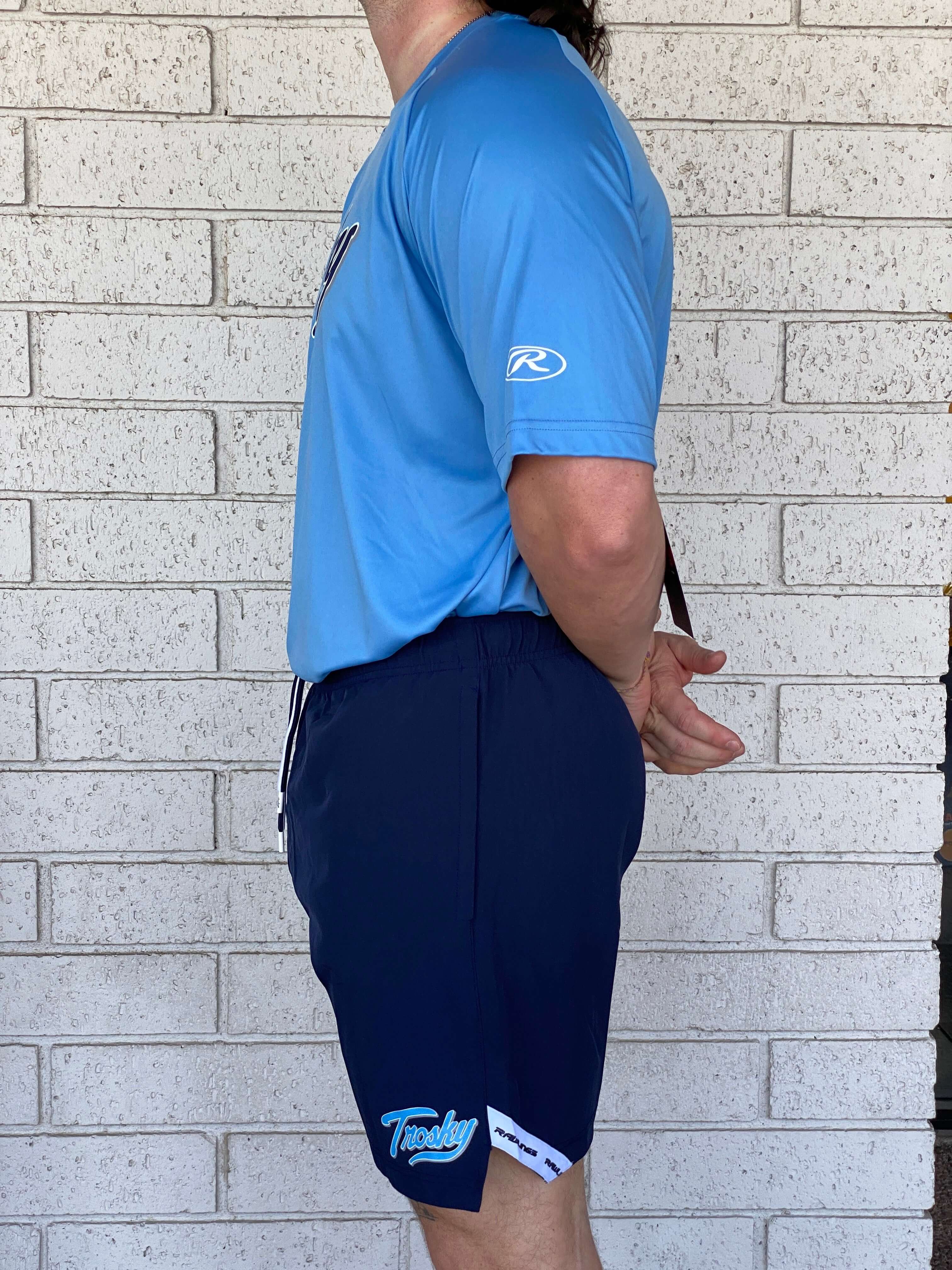 Man in blue athletic shirt and navy Rawlings Trosky Shorts, showcasing contemporary sports style and comfort.