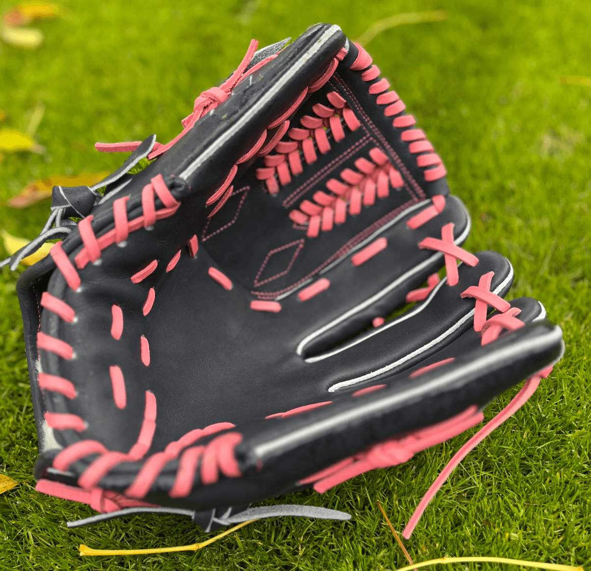 Detail of pink thread and pink laces against navy glove showcasing style.