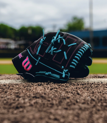 Wilson A2000 B2 pitcher's glove in black and teal, featuring closed 2-piece web, on a baseball field.