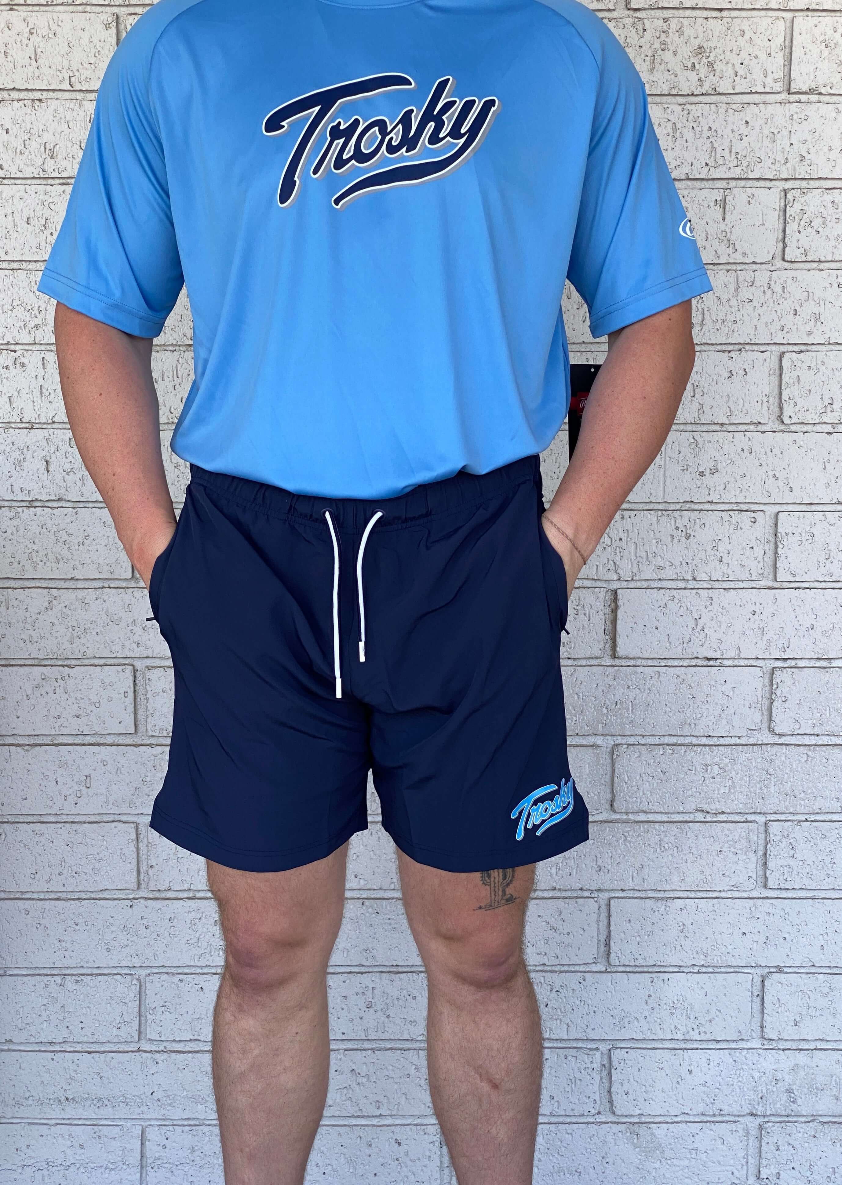 Man wearing Rawlings Trosky Shorts in navy, paired with a blue shirt, showcasing athletic wear style and comfort.