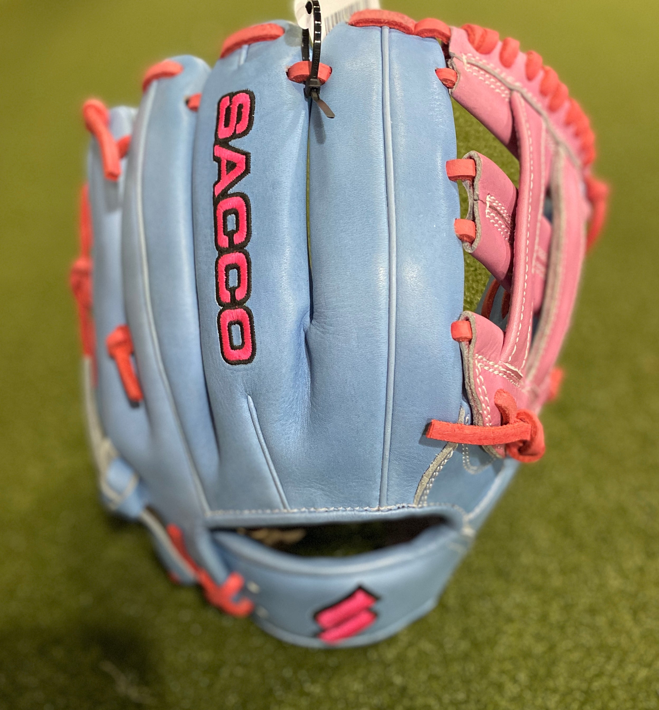 Sacco Ultra Smooth Kip RHT H-Web Cotton Candy 11.5" glove on grass, featuring durable blue and pink leather design.